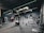 A modern gym interior equipped with various fitness machines such as treadmills, rowing machines, and a punching bag. The room has a dark color scheme with green accent lighting running across the ceiling and walls. The floor is carpeted, and there's a sense of tidy organization.