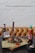 A meal setup features grilled chicken on a wooden board with a knife inserted into it, accompanied by a small bowl of sauce with red pepper flakes. There's a bottle of beer in a mason jar and a sriracha hot sauce bottle beside it on a dark wooden table, set against a tufted leather bench and a white brick wall.