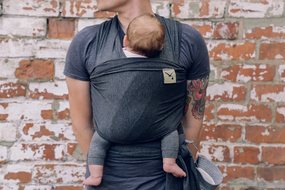 a man holding a baby in a sling