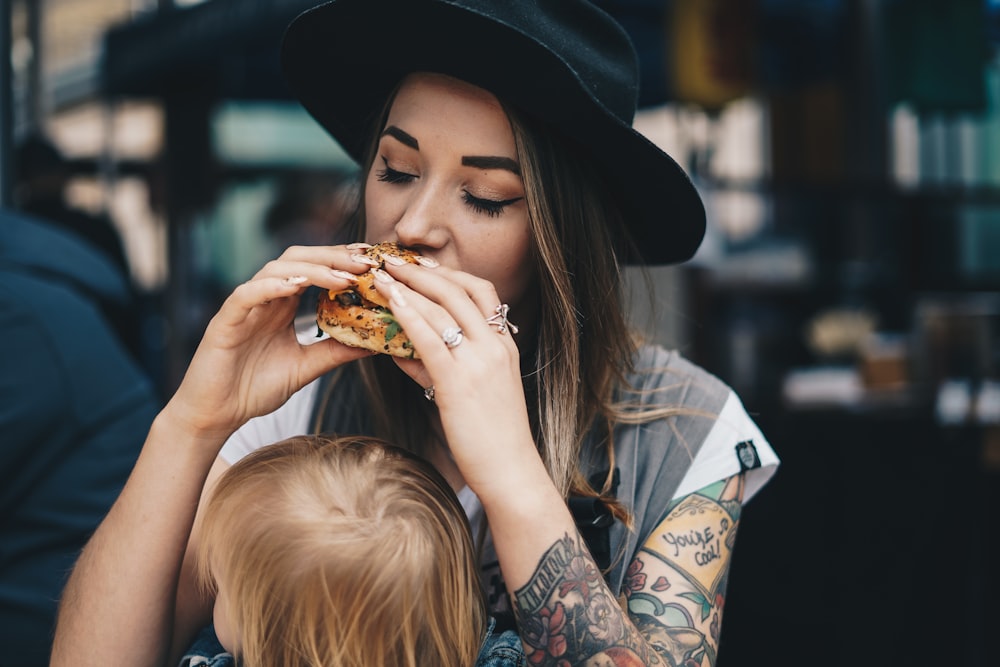 a woman in a black hat is eating a piece of pizza