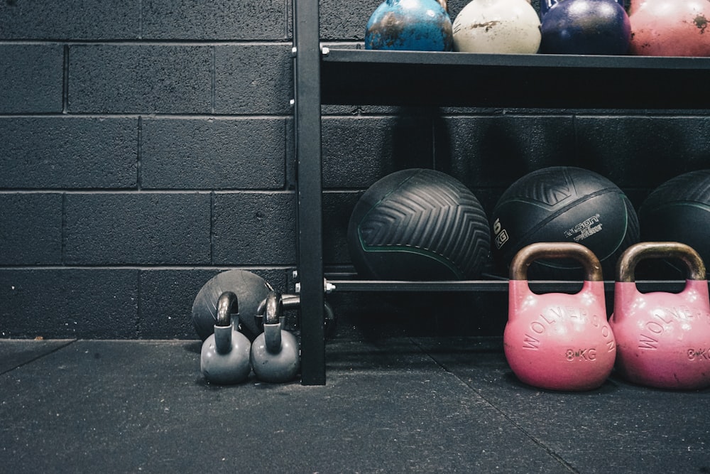 a rack filled with different colored kettles next to a brick wall