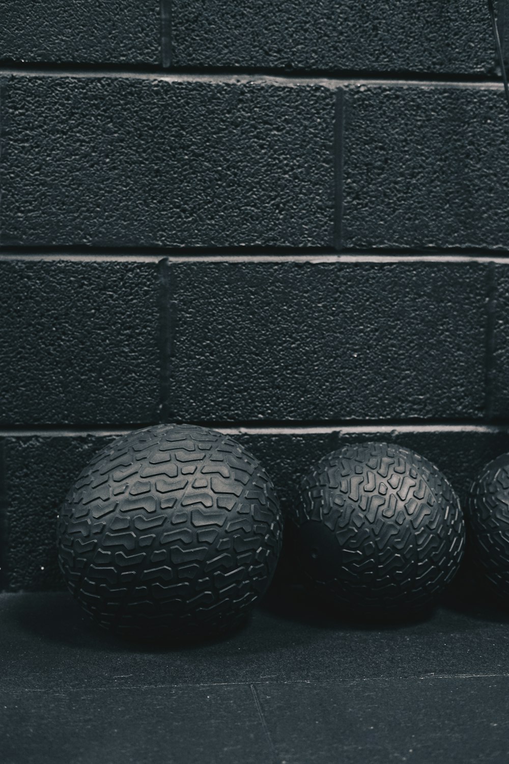 three black balls sitting next to a brick wall