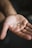 A close-up of a hand holding a natural supplement capsule with a green leaf in the background.