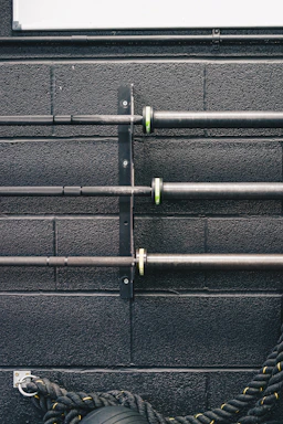 Close-up of a rugged powerlifting belt and chalk bag resting on a gym bench under bright lights.