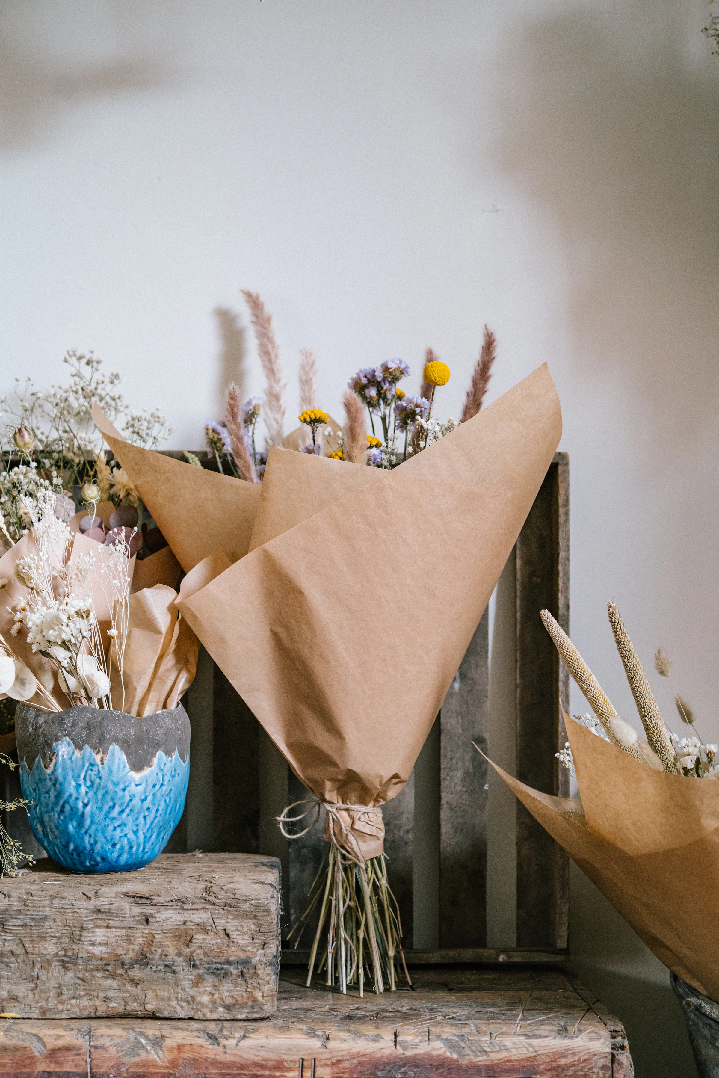 Hand-tied dried and seasonal flower bouquets wrapped in kraft paper — a snapshot of the everyday craft behind the sustainable floristry classroom.