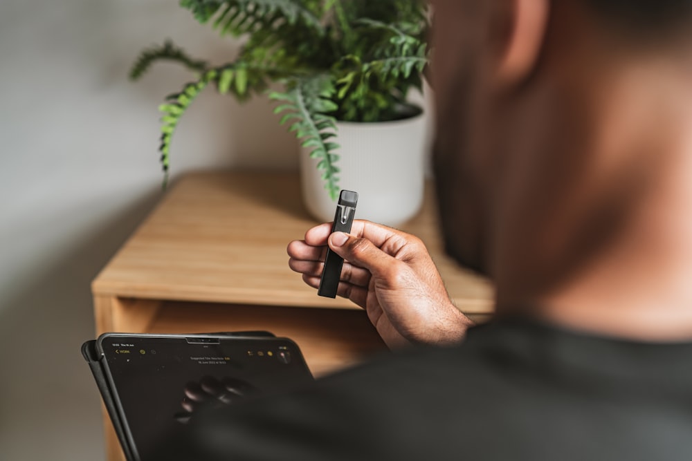 a man sitting at a desk with a laptop and a plant