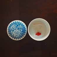 An elegant bamboo bowl filled with colorful capsules on a wooden surface.