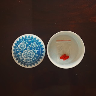 An elegant bamboo bowl filled with colorful capsules on a wooden surface.