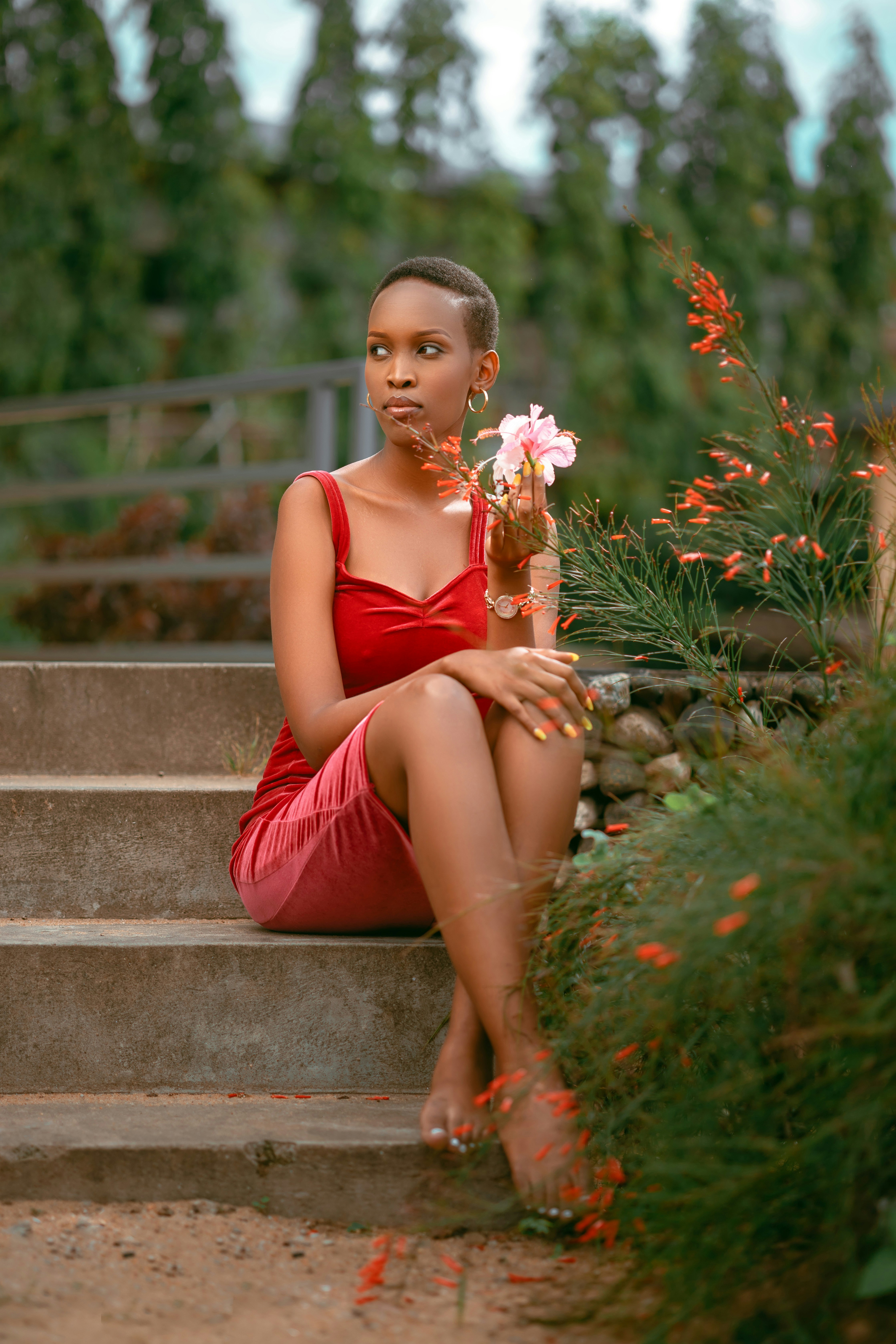 A woman in a red dress sitting on steps holding a flower photo – Free ...