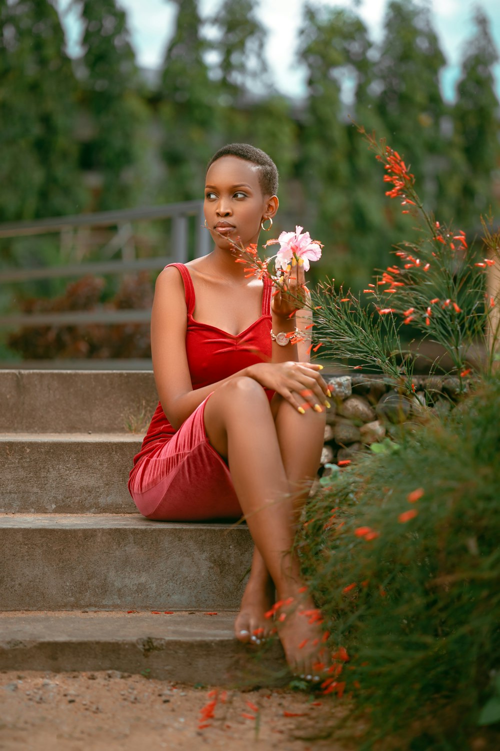 빨간 드레스를 입은 여자가 꽃을 들고 계단에 앉아 있다