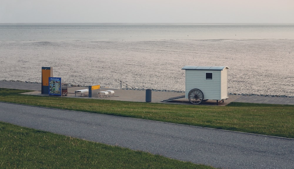 a small white building sitting on the side of a road next to the ocean