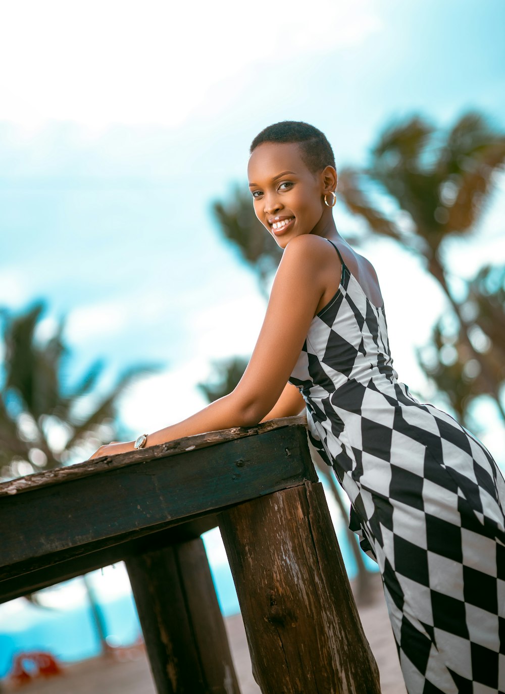 a woman in a checkered dress leaning on a rail