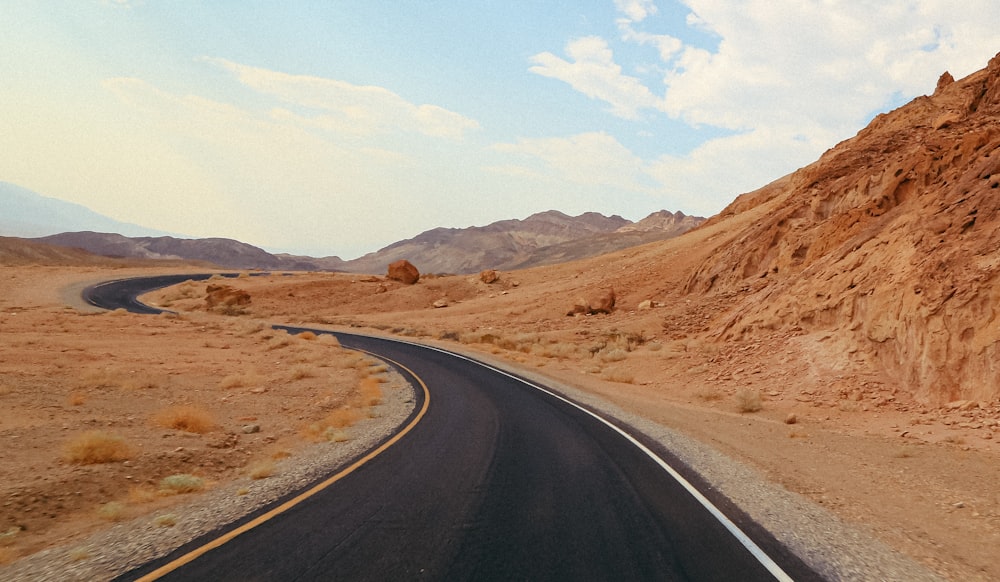 a road in the middle of a desert with a mountain in the background
