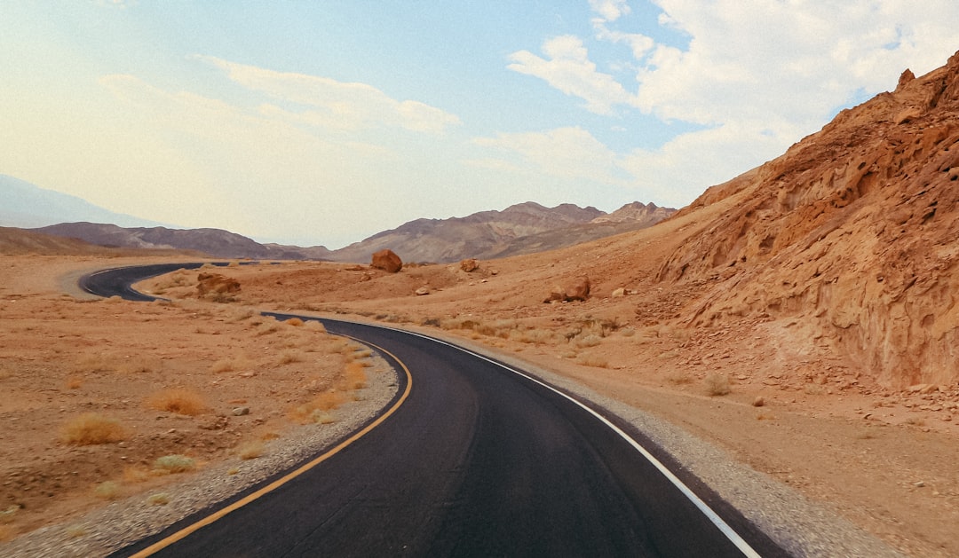 a road in the middle of a desert with a mountain in the background,
