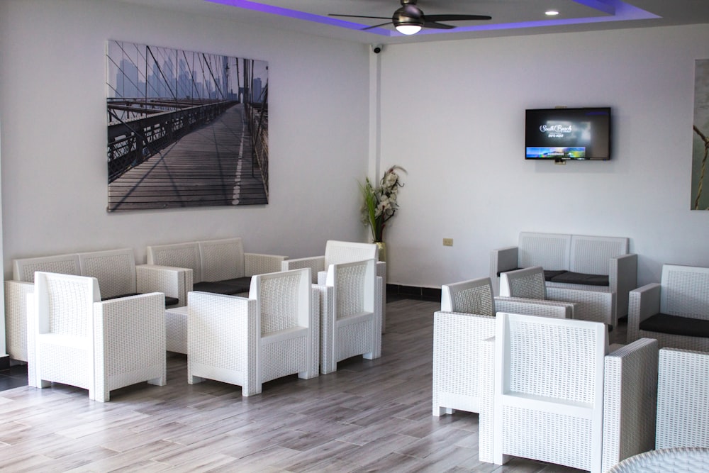 a room filled with white wicker furniture and a flat screen tv