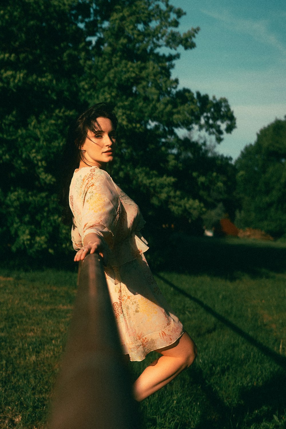 a woman leaning on a rail in a field