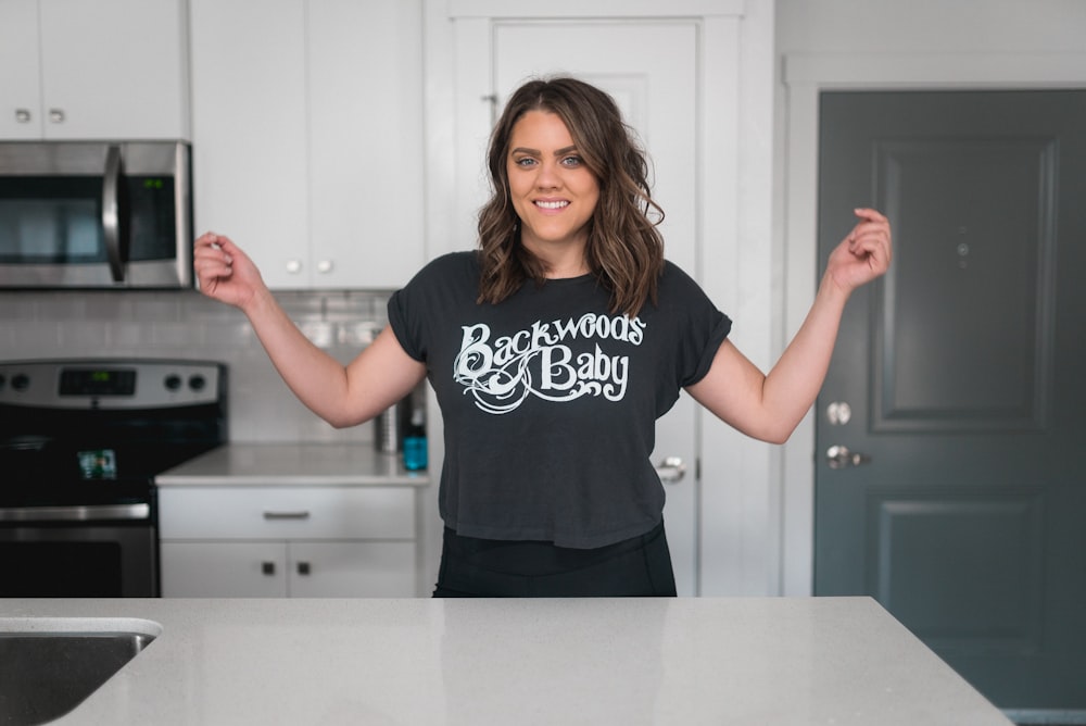 a woman standing in a kitchen with her hands in the air