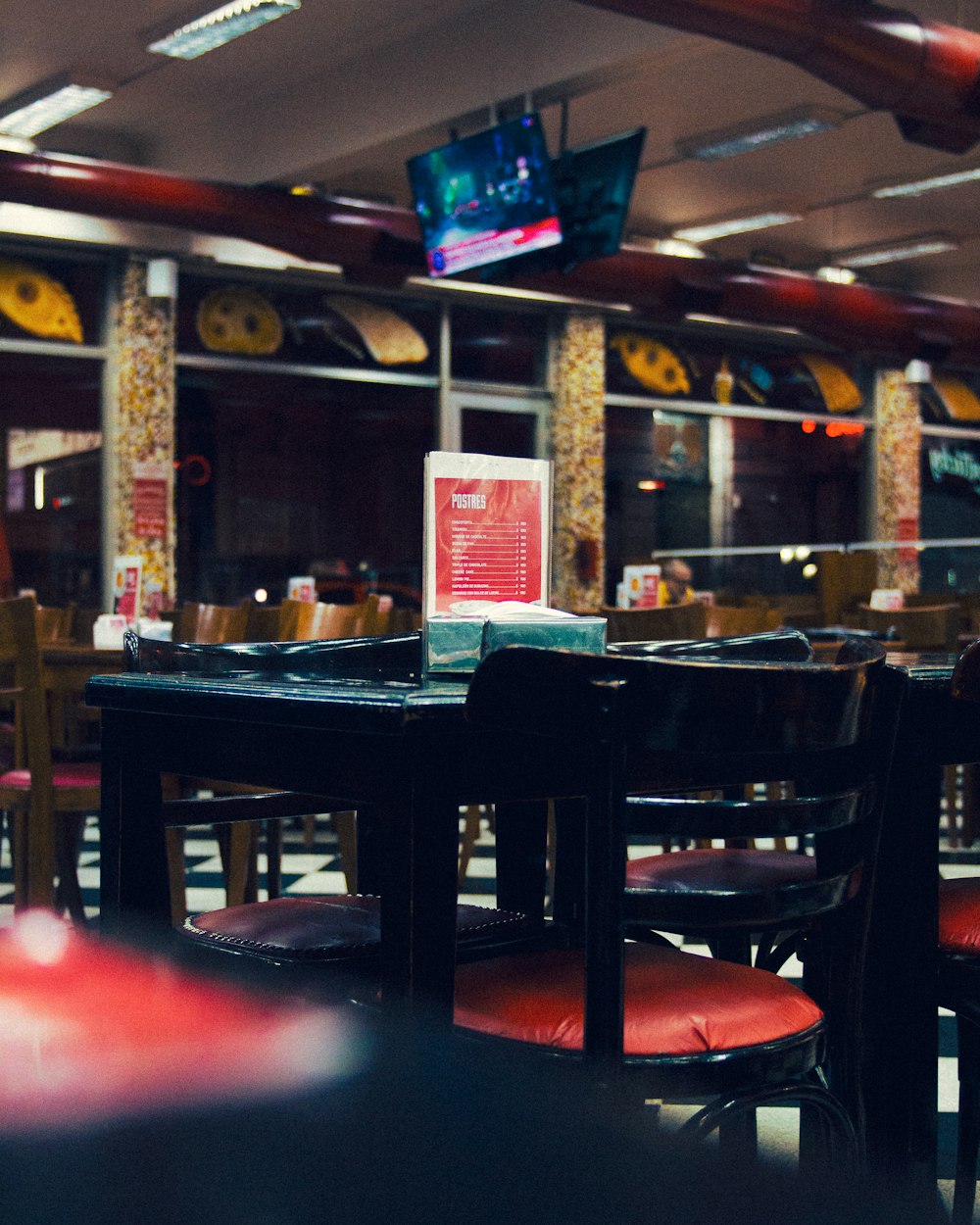 a table and chairs in a restaurant with a television in the background