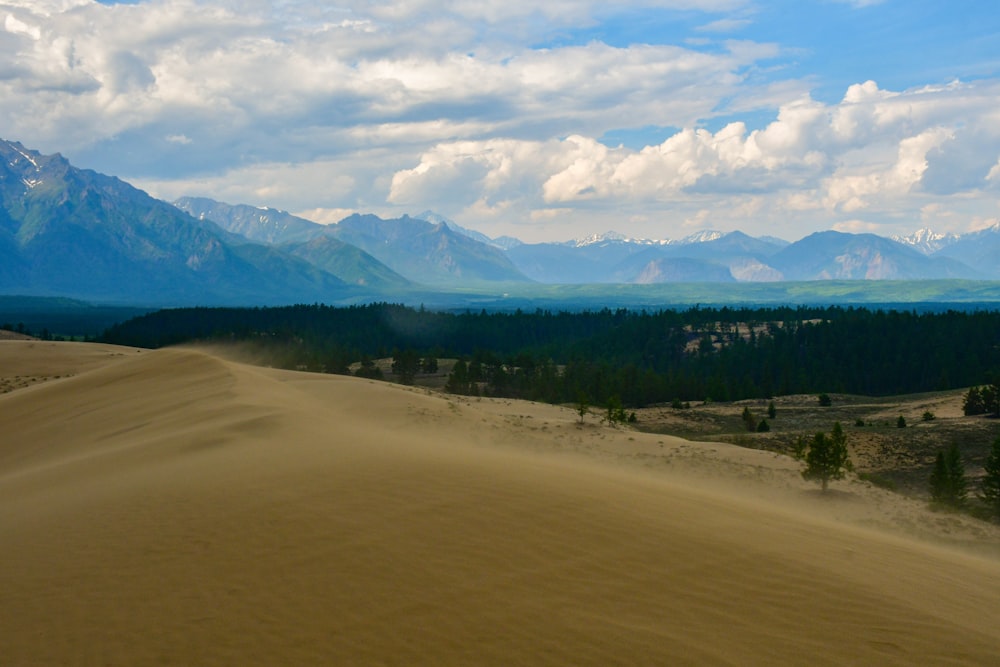 a large sand dune with mountains in the background