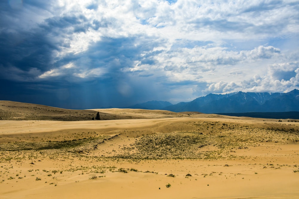 a large sandy field with mountains in the background