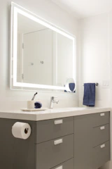 Modern white vanity with black countertop and integrated smart mirror glowing gently.