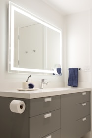 A modern bathroom mirror with sleek frame reflecting a bright, clean space.