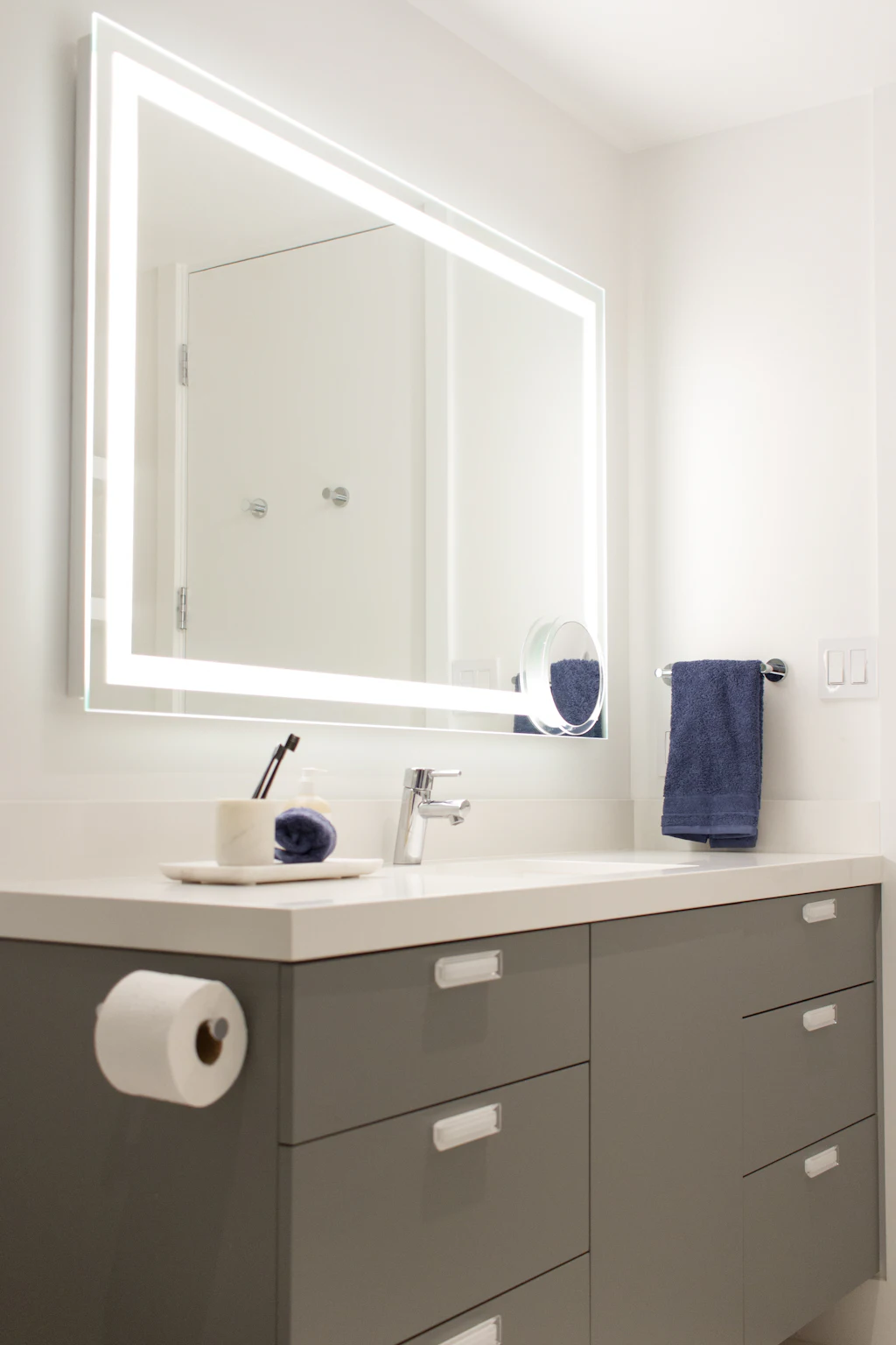 Lavabo et miroir éclairé avec des serviettes bleues