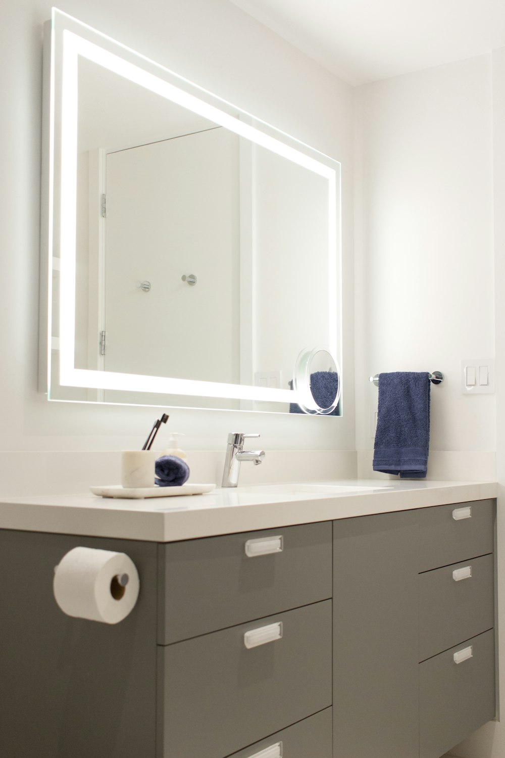 a bathroom with a sink, mirror and toilet paper