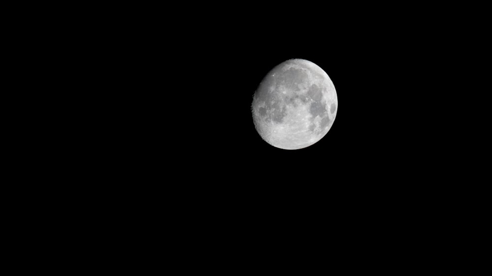 a full moon is seen in the dark sky