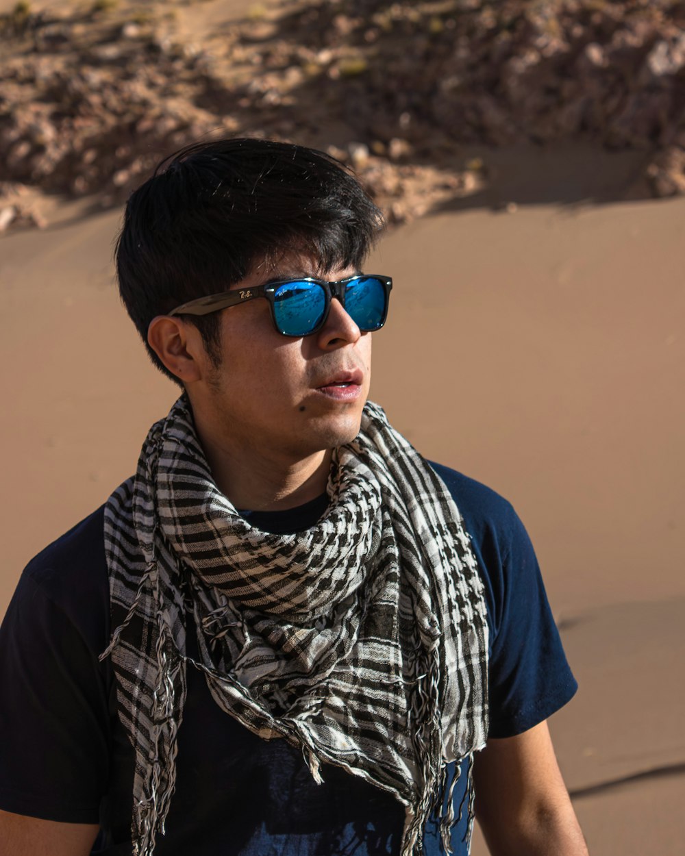 a man wearing sunglasses and a scarf on a beach