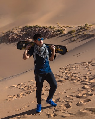 a man holding a skateboard in the desert