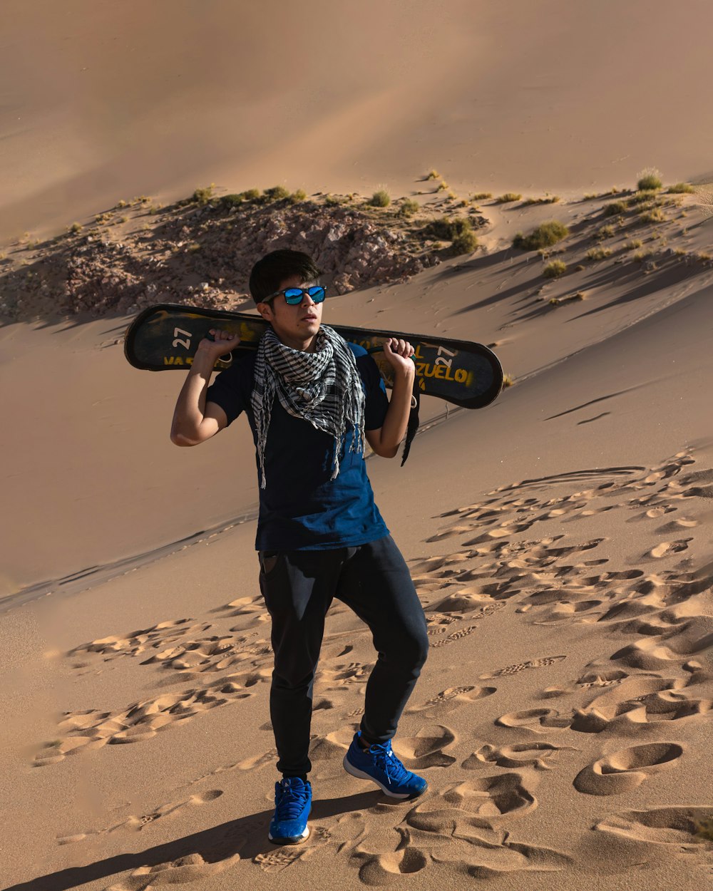 Ein Mann, der ein Skateboard in der Wüste hält