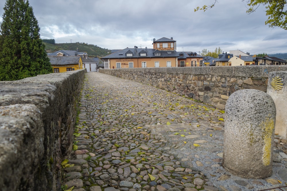 a cobblestone road leading to a building with a clock tower in the background