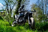A rider in leather gear cruising through a forest trail.