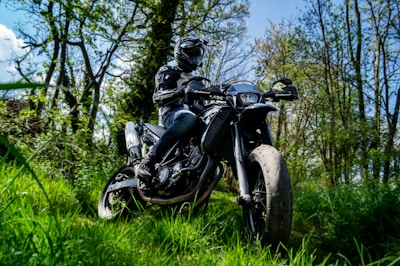 A rider in leather gear cruising through a forest trail.