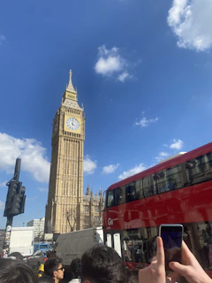 Happy travelers posing in front of London's Big Ben on a bright, clear day.