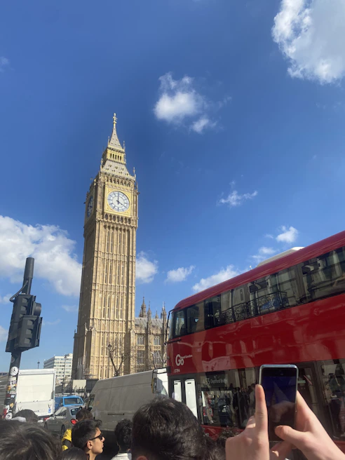Happy travelers posing in front of London's Big Ben on a bright, clear day.