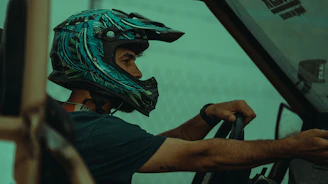 Close-up of a happy customer wearing a helmet, sitting in a bright red x-buggy with mountains in the background.