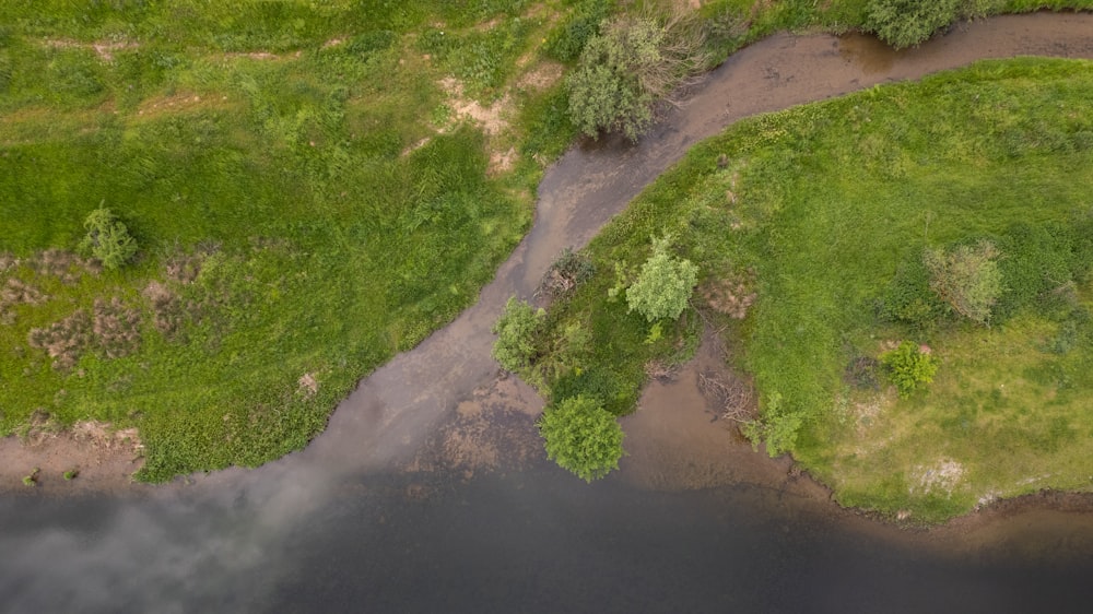 an aerial view of a river running through a lush green field