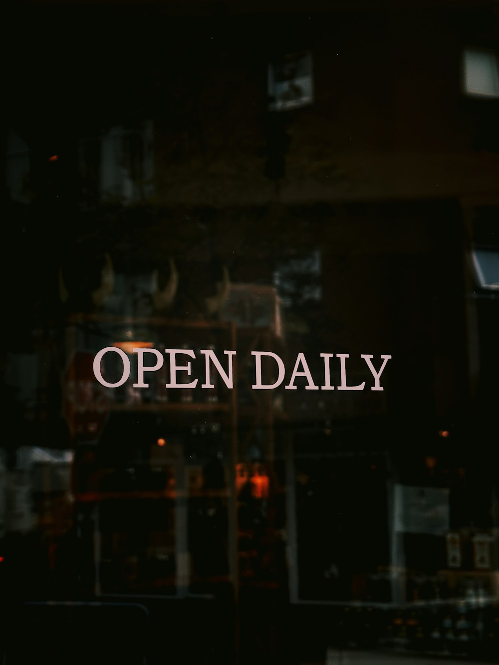 an open daily sign is reflected in a window
