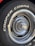 Close-up of a car tire with the words 'COOPER COBRA' prominently displayed in white letters on the black rubber surface. The tire is mounted on a metal rim with intricate, radial design and a shiny, reflective central hubcap.