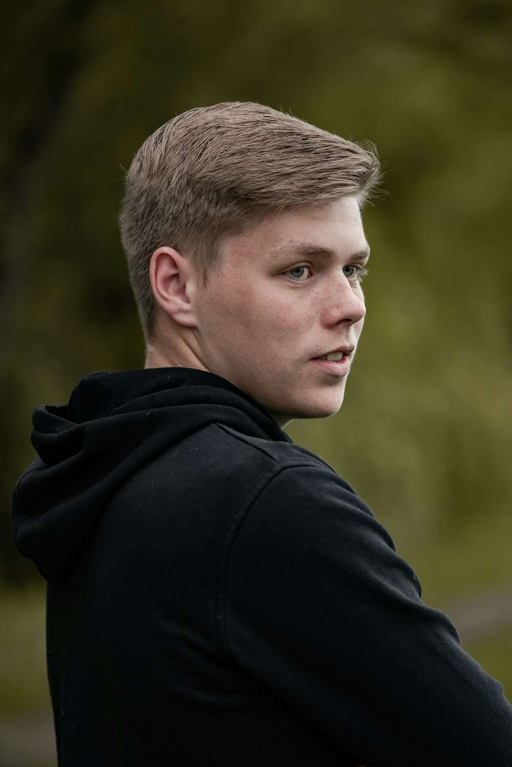a young man in a black hoodie looking off into the distance
