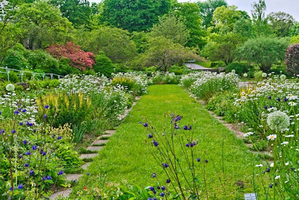 A vibrant garden with a mix of colorful flowers, lush green lawn, and a modern stone pathway.