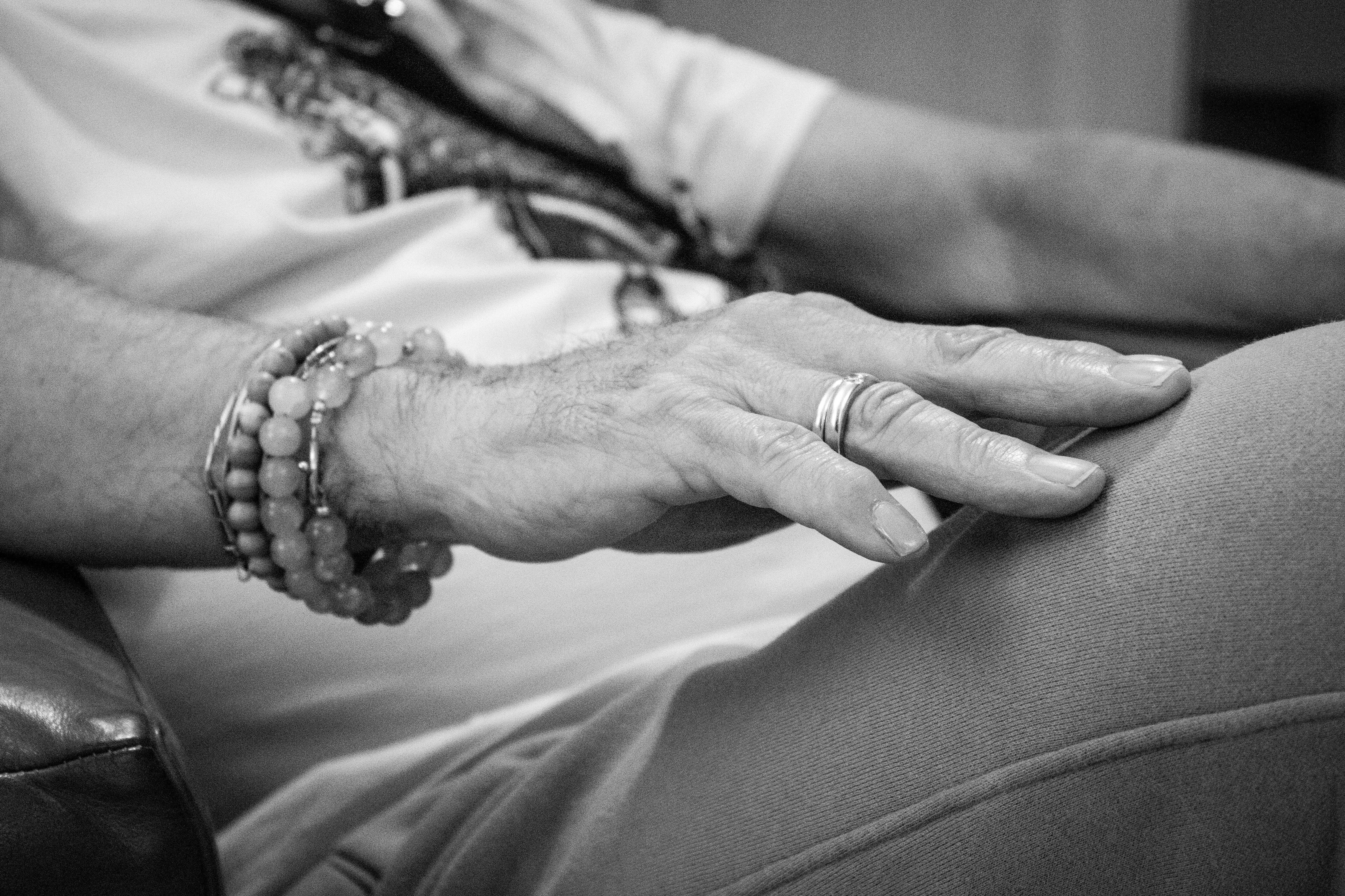 a black and white photo of a person's hand resting on a chair