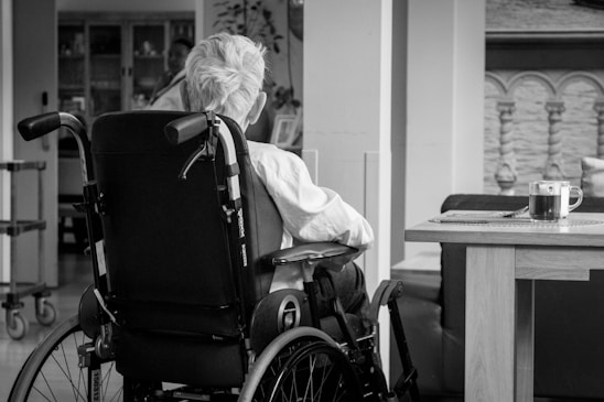 A caring caregiver helping an elderly person with a wheelchair in a cozy home setting.