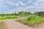 A beautifully maintained garden featuring neatly organized flower beds and lush greenery. Pathways divide the garden into sections, with colorful flowers and well-trimmed bushes adding to the picturesque landscape. The sky above is partly cloudy, providing a serene backdrop.