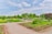 A beautifully maintained garden featuring neatly organized flower beds and lush greenery. Pathways divide the garden into sections, with colorful flowers and well-trimmed bushes adding to the picturesque landscape. The sky above is partly cloudy, providing a serene backdrop.