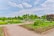 A beautifully maintained garden featuring neatly organized flower beds and lush greenery. Pathways divide the garden into sections, with colorful flowers and well-trimmed bushes adding to the picturesque landscape. The sky above is partly cloudy, providing a serene backdrop.