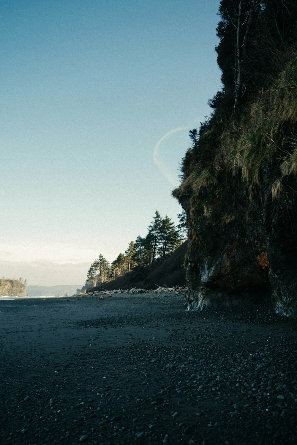 a person standing on a beach next to a cliff