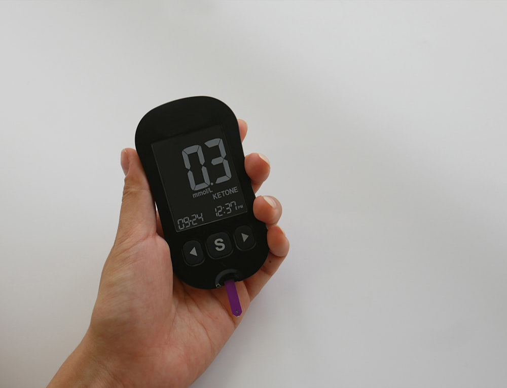 a hand holding a digital thermometer on a white surface